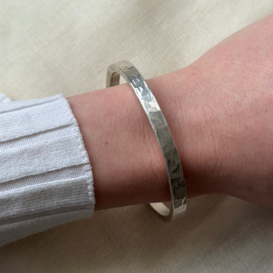 Silver bracelet on a wrist with a light background
