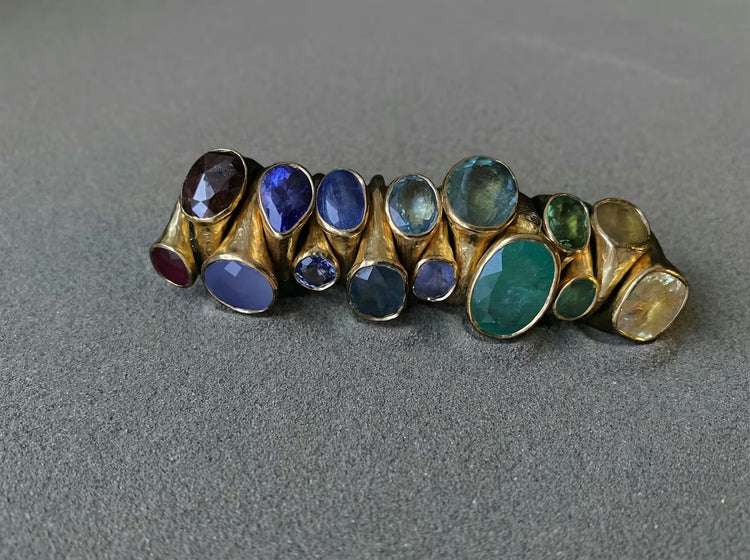 22ct gold gemstones jewellery handcrafted on grey sand.