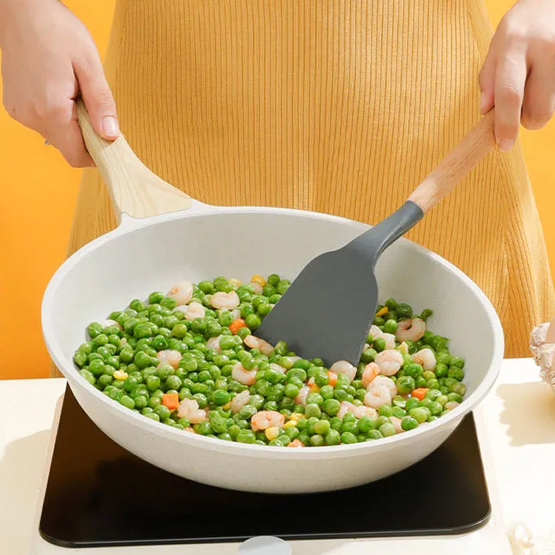 Person cooking peas and shrimp in a white bowl with a spatula on a yellow background