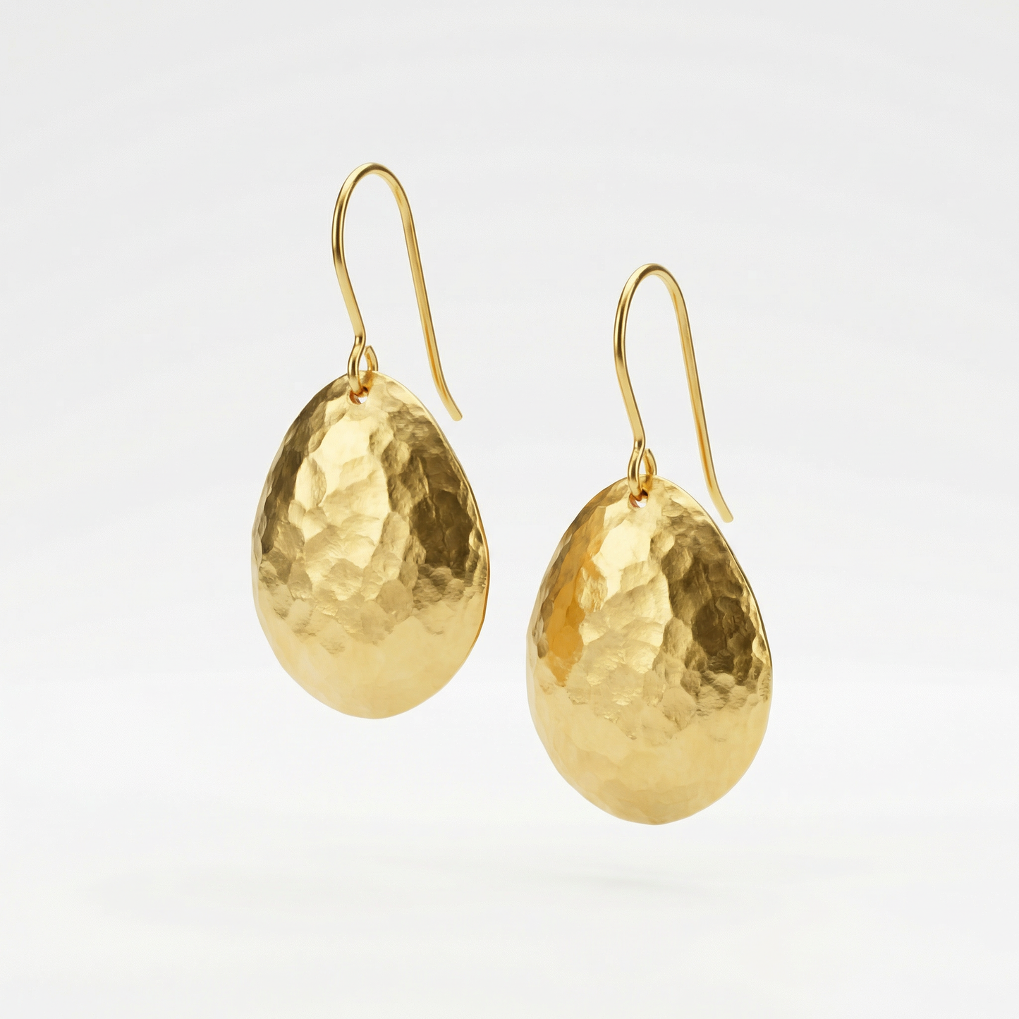 Gold earrings on a light gray background