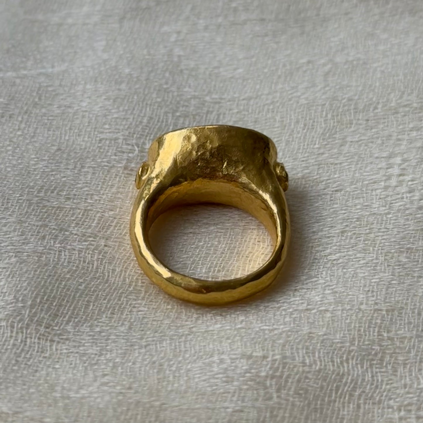 22ct Gold ring with Emerald on a textured gray background.