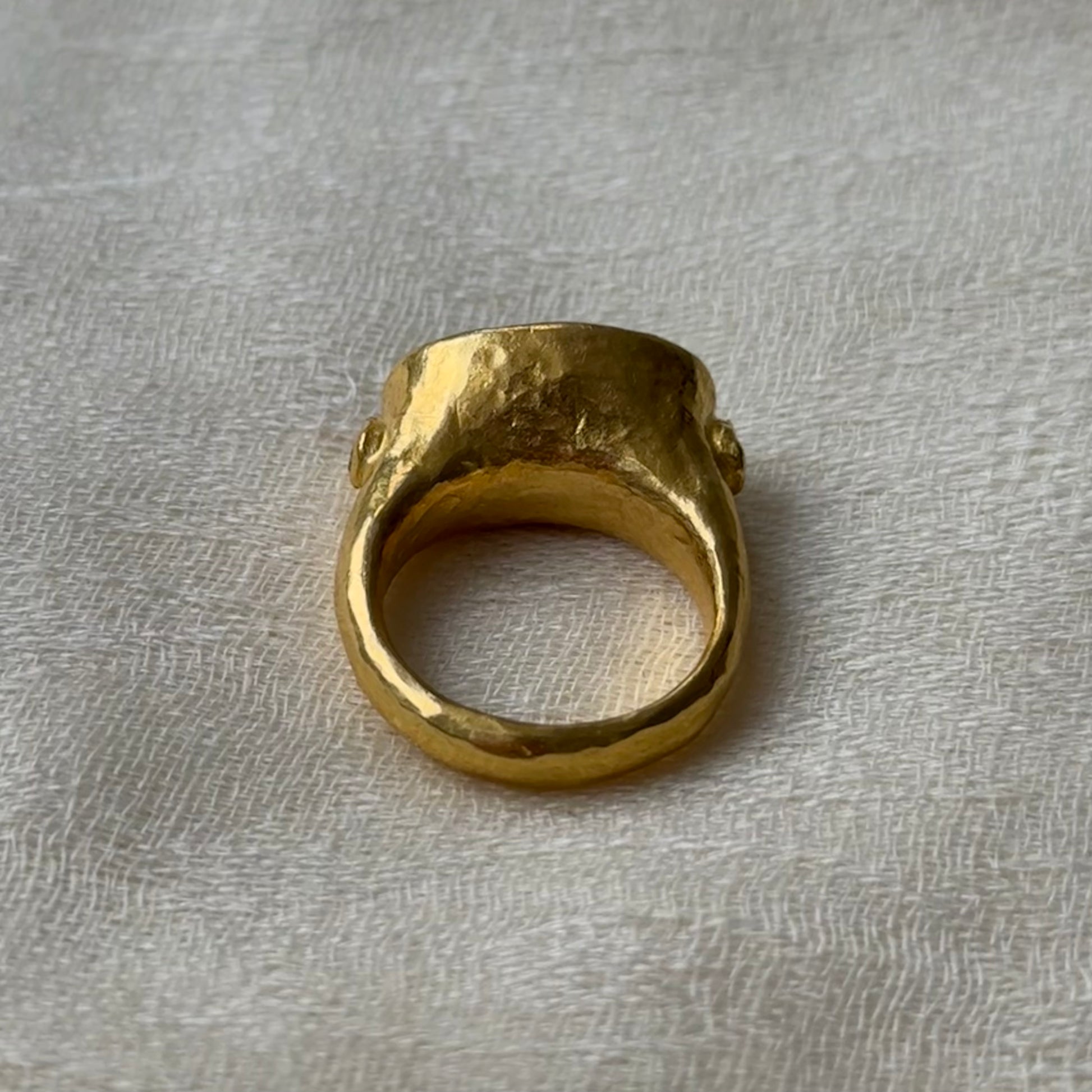 22ct Gold ring with Emerald on a textured gray background.