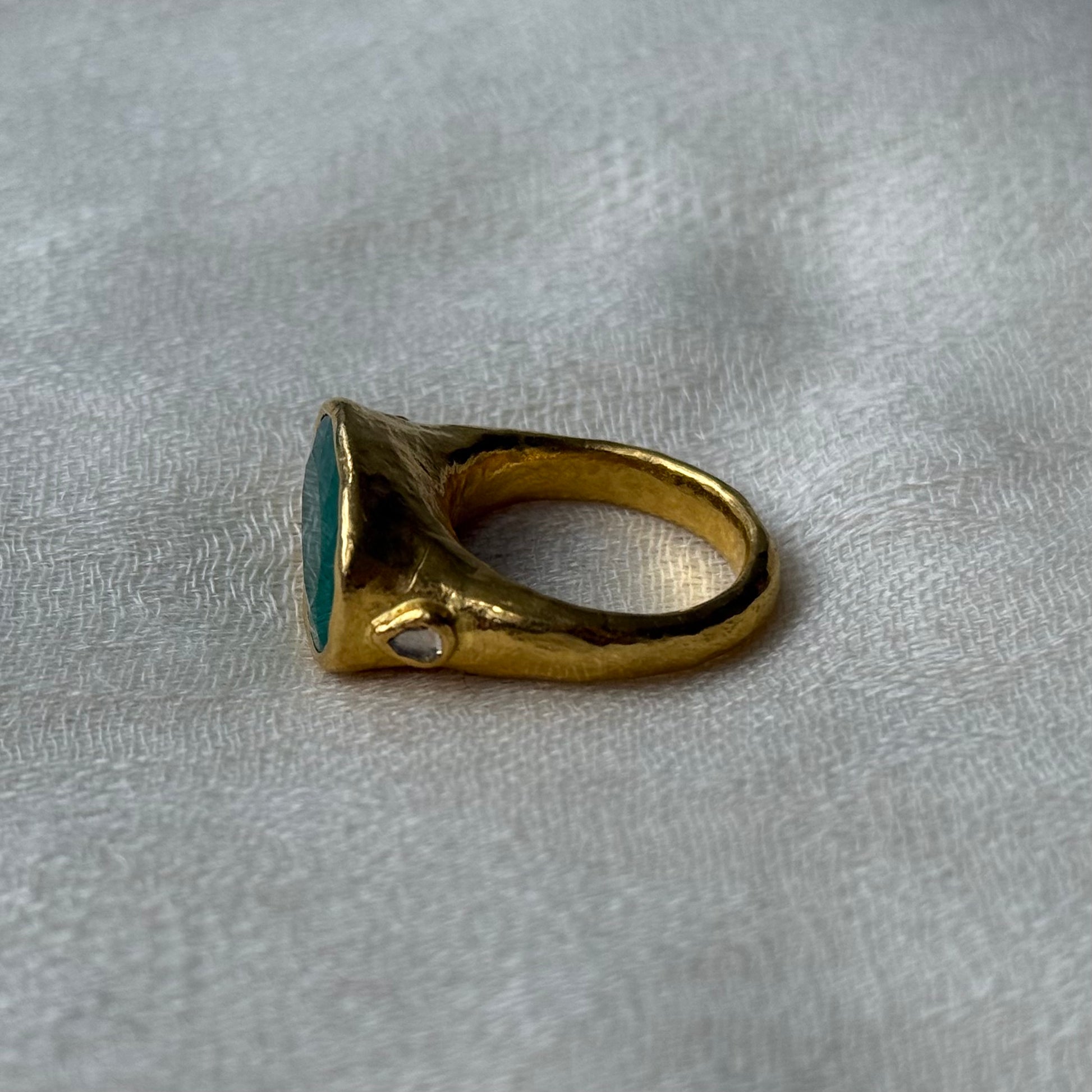 22ct Gold ring with a Emerald gemstone on a textured white background