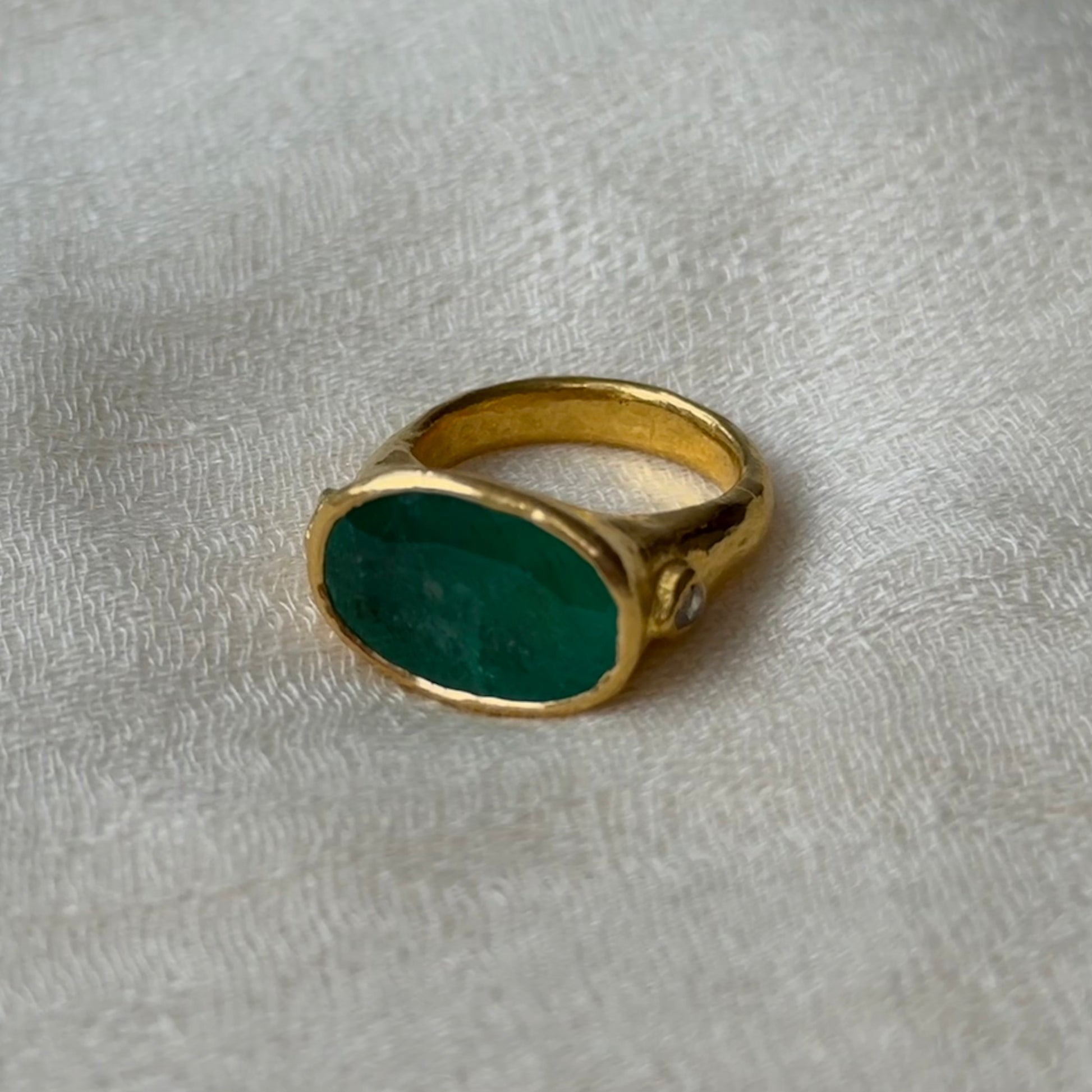 22ct Gold ring with a Emerald stone on a textured gray background