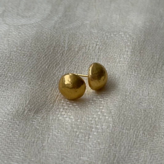 Pair of 22ct gold stud earrings on a textured gray surface