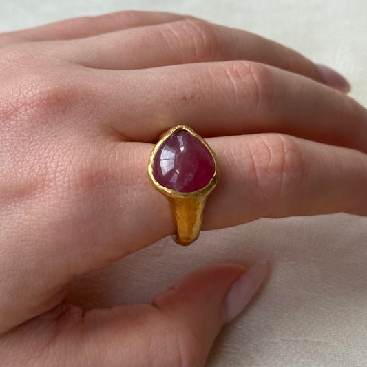 22ct Gold ring with a Ruby gemstone on a hand against a neutral background