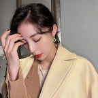 Woman wearing a beige coat with a neutral background