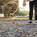 Person using a rope to pull something on a gravel surface with close-up details of the equipment.