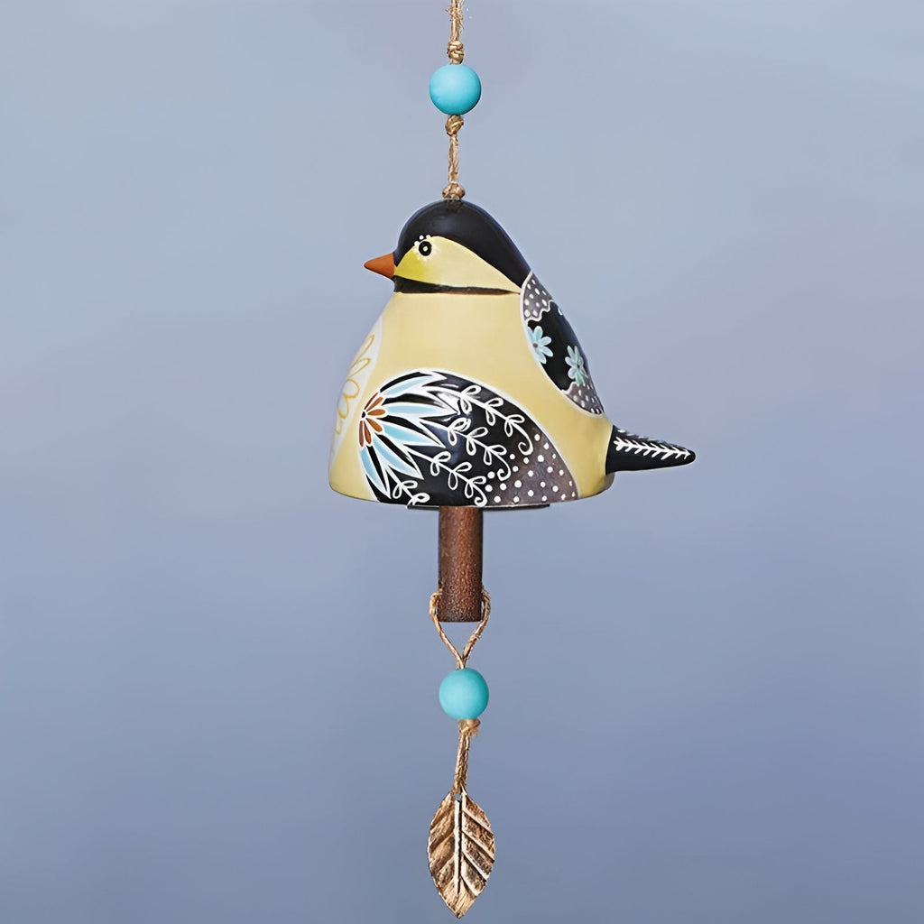 Decorative hanging bird ornament with turquoise beads and a gold leaf on a light blue background