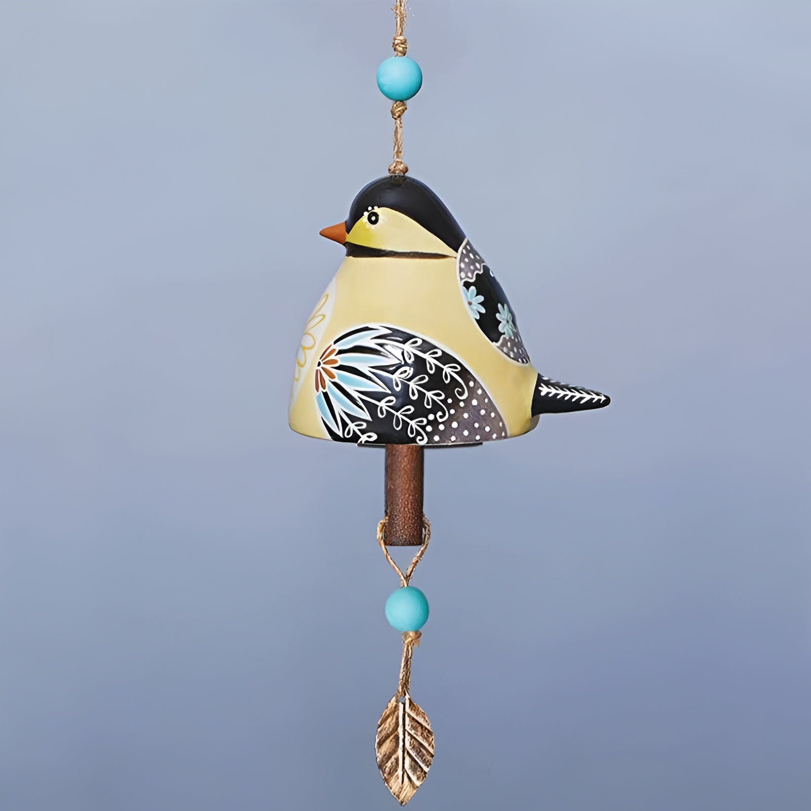 Decorative hanging bird ornament with turquoise beads and a gold leaf on a light blue background