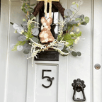 Decorative wreath with a rabbit and greenery on a door with house number 5
