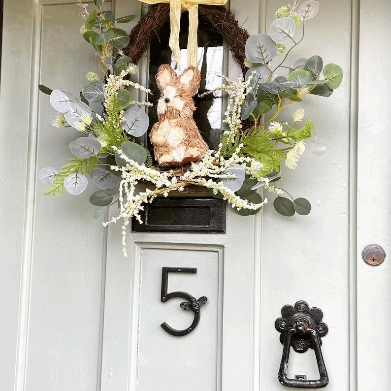 Decorative wreath with a rabbit and greenery on a door with house number 5