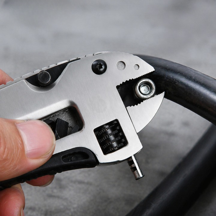 Multi-tool with various attachments held by a hand against a blurred background