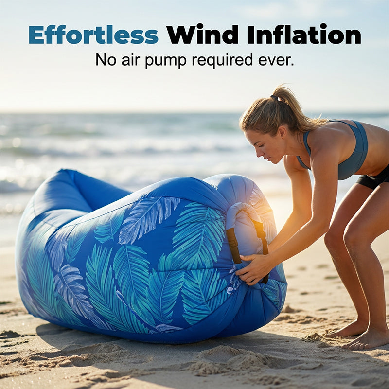 Woman inflating a blue inflatable lounge on a beach with text about effortless wind inflation.