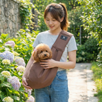 Woman holding a small brown dog in a brown sling carrier amidst flowers and greenery.