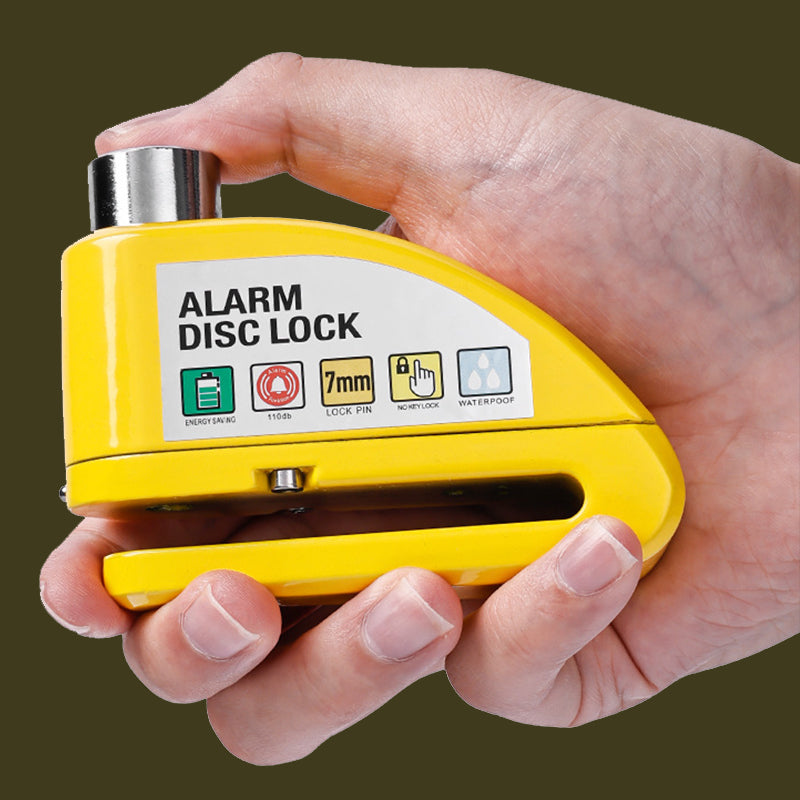 Yellow alarm disc lock held in a hand with a dark background