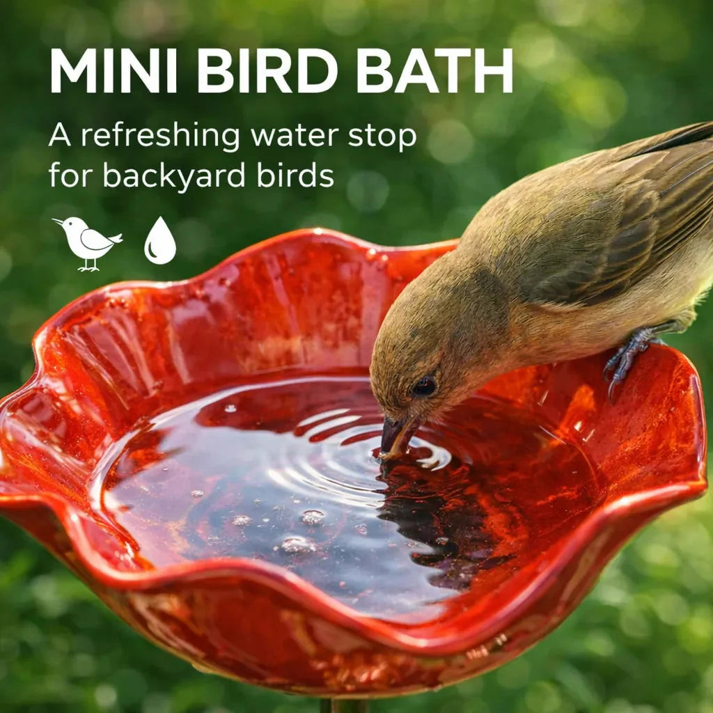 Red mini bird bath with a bird drinking water, set against a green background.