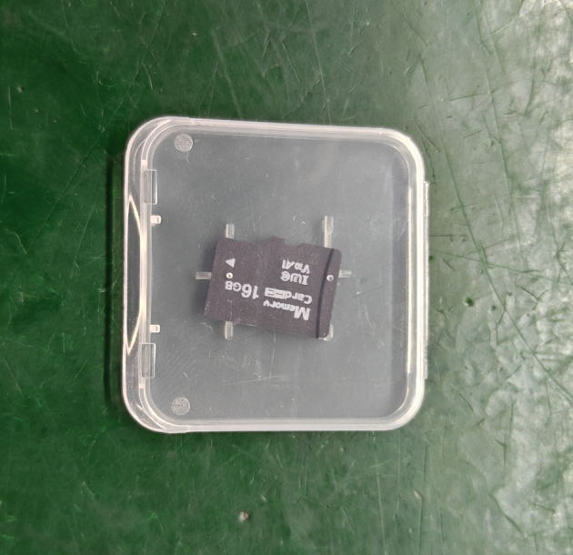 Small electronic component in a clear plastic container on a green surface