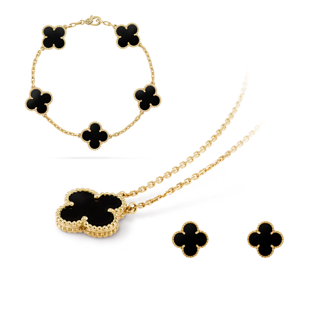 Gold jewelry set with black clover-shaped stones on a white background