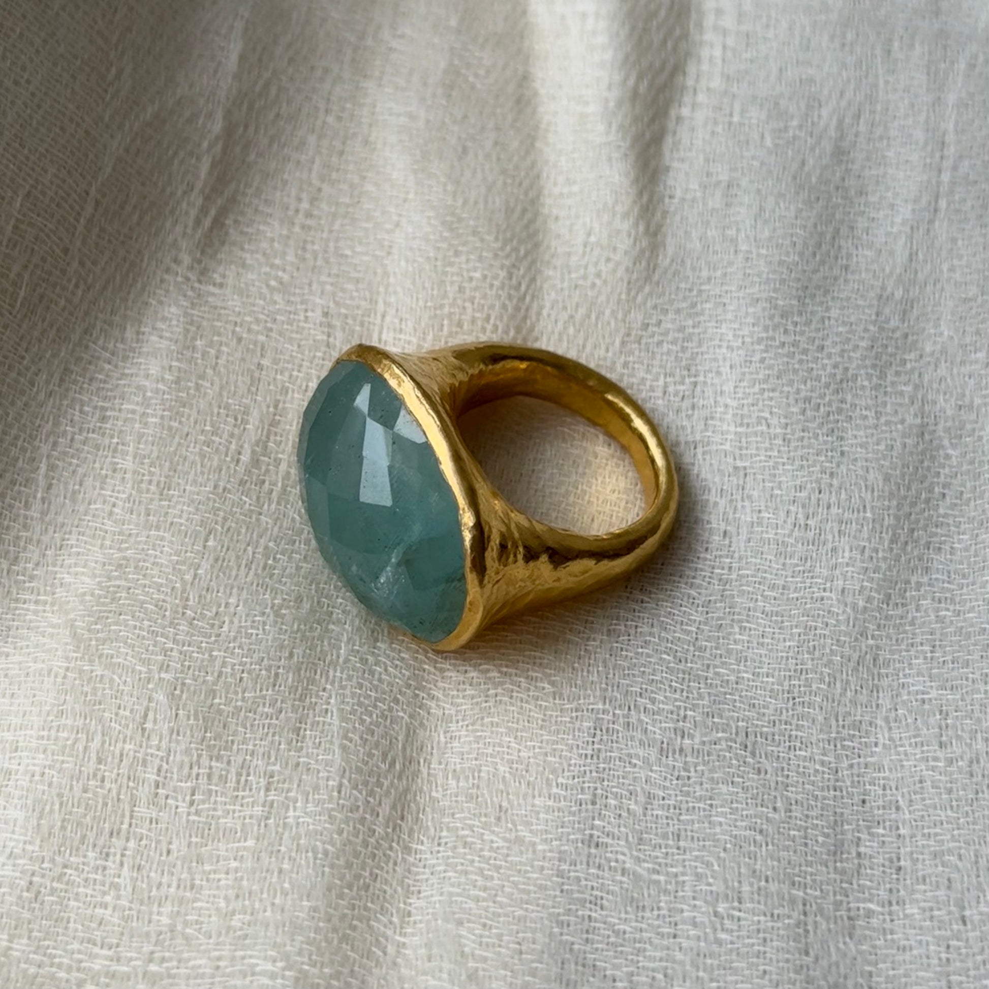 22ct solid Gold ring with a Aquamarine gemstone on a textured beige fabric background