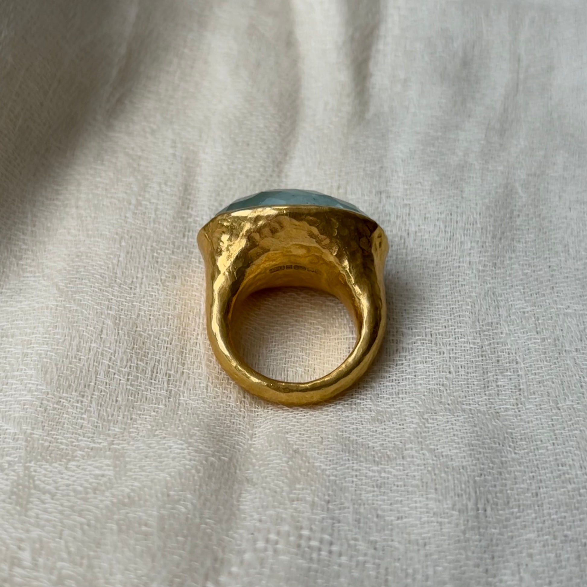 22ct Gold ring with a blue Aquamarine stone on a light fabric background