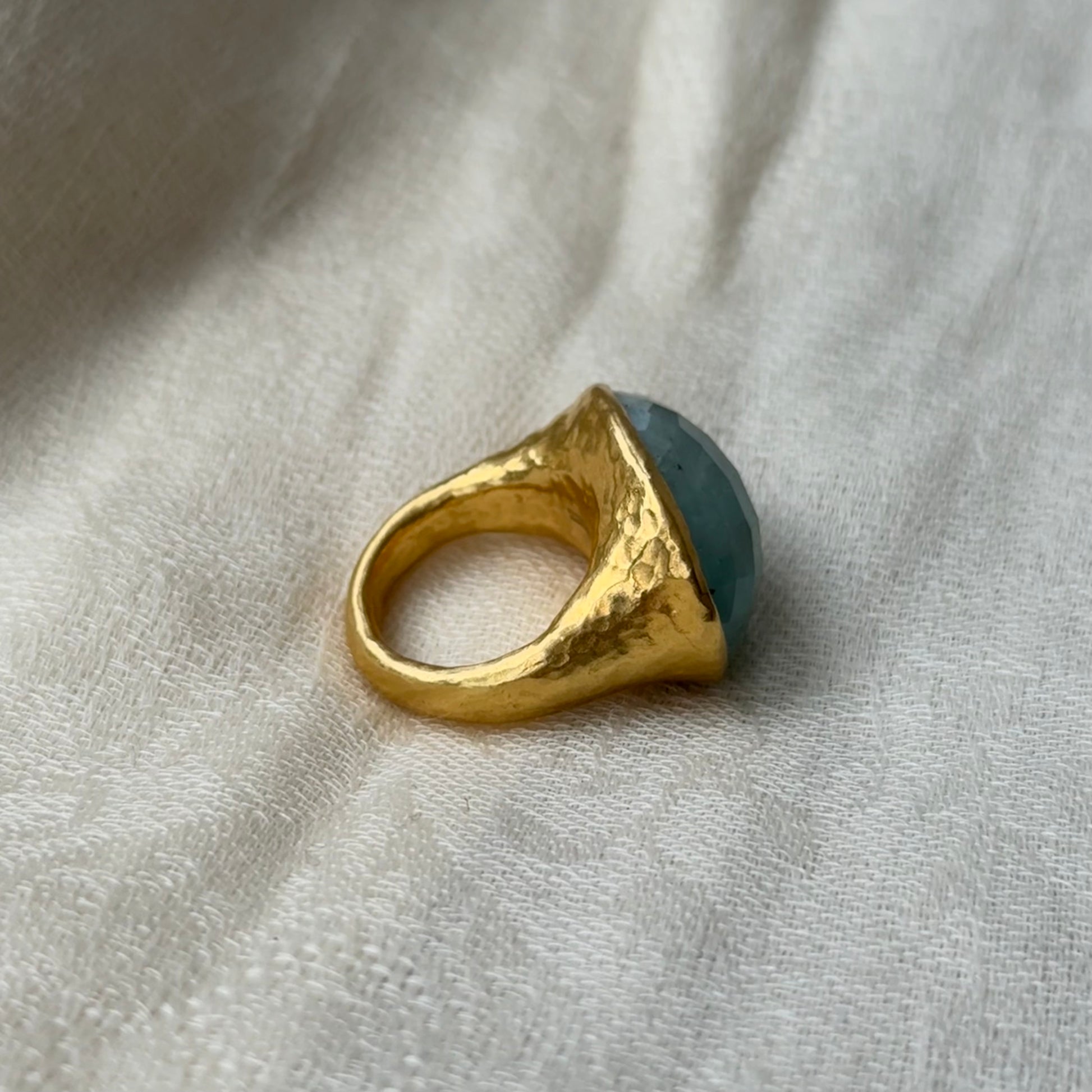22ct Gold ring with a blue Aquamarine stone on a light fabric background