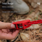 Red adjustable strap with twist design held by a hand, blurred natural background