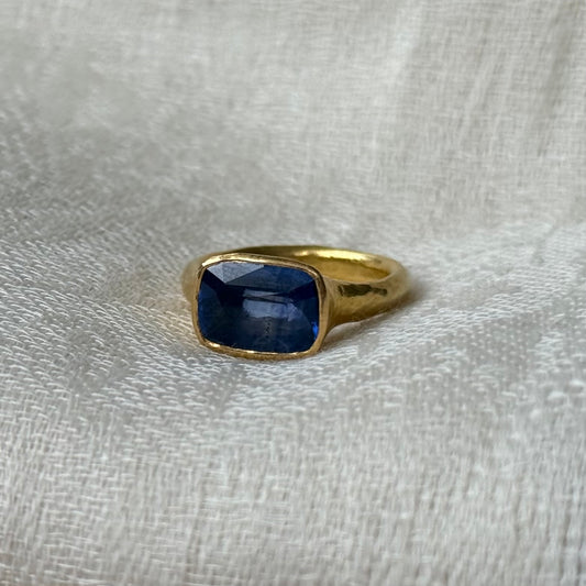 22ct Gold ring with a blue Tourmaline gemstone on a light gray fabric background
