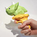 Hand holding a green and yellow geometric dinosaur toy against a white background