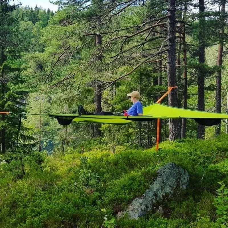 Person using a green tree tent in a forest setting