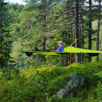 Person using a green tree tent in a forest setting