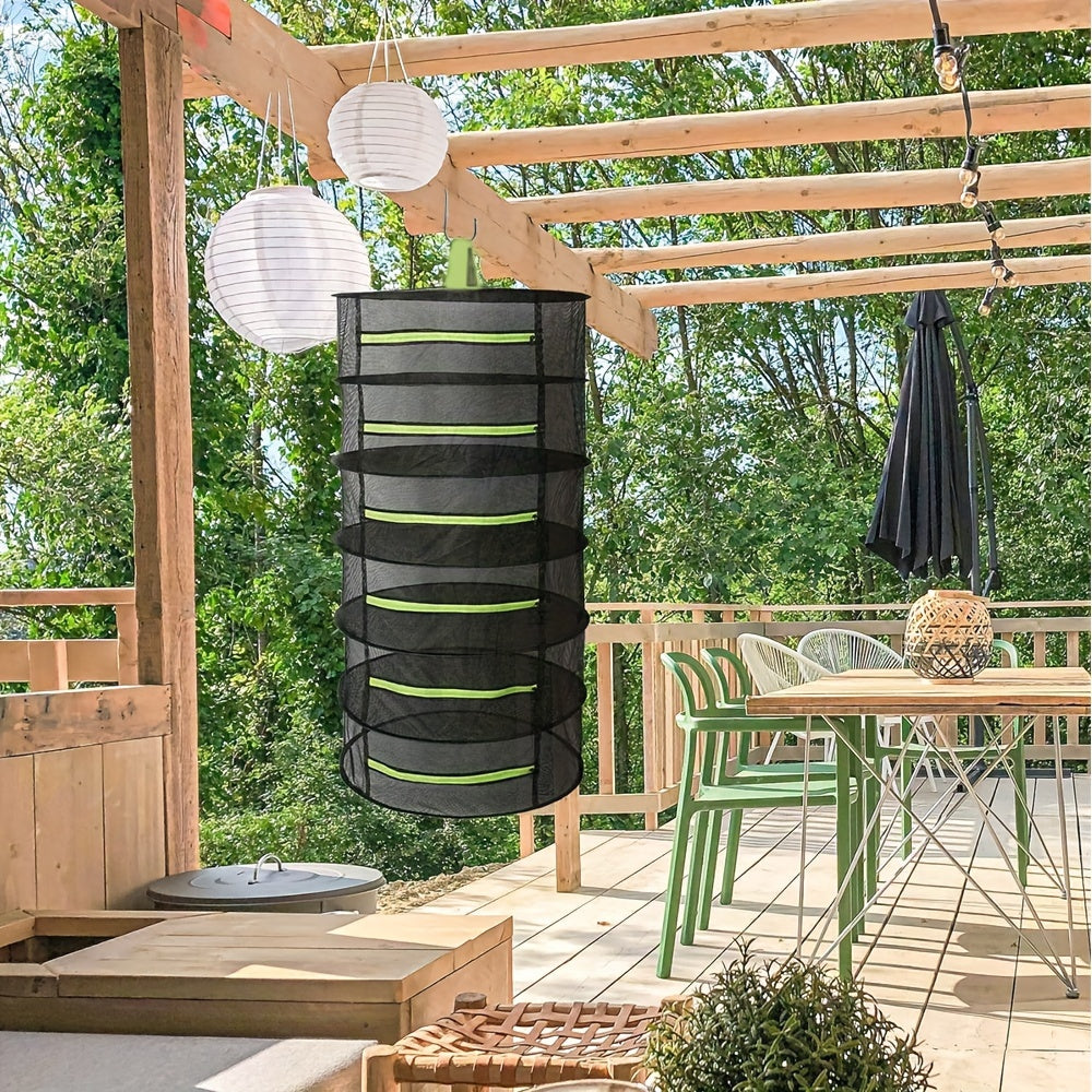 Black hanging plant holder with green stripes on a wooden deck with greenery in the background