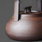 Close-up of a wooden teapot with a dark brown finish on a gray background