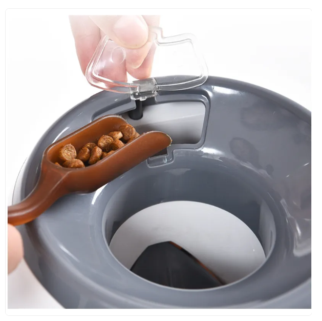 Gray pet food bowl with a brown scoop containing dog food, being filled by a hand.
