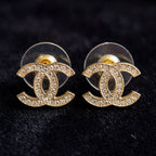 Gold Chanel earrings with clear gemstones on a black background
