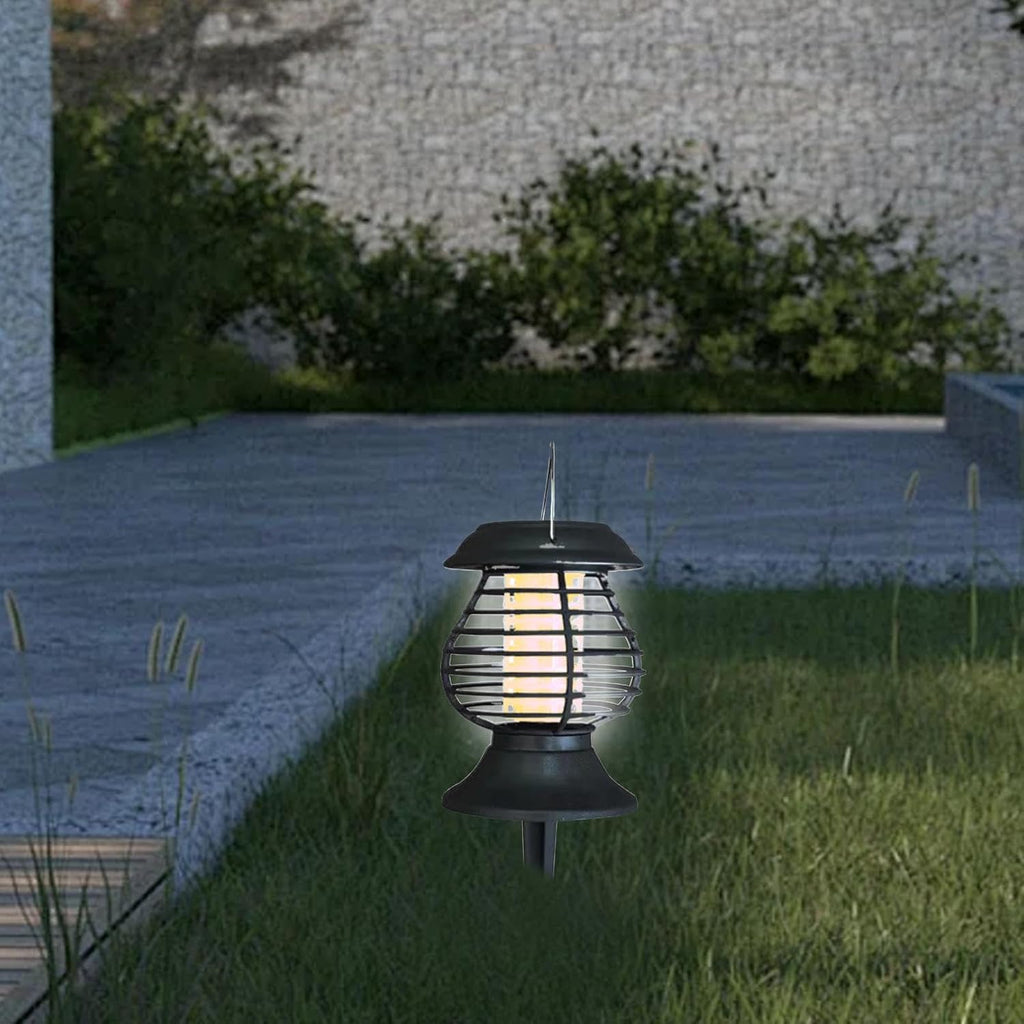 Solar-powered outdoor light fixture on grass with a stone wall and plants in the background