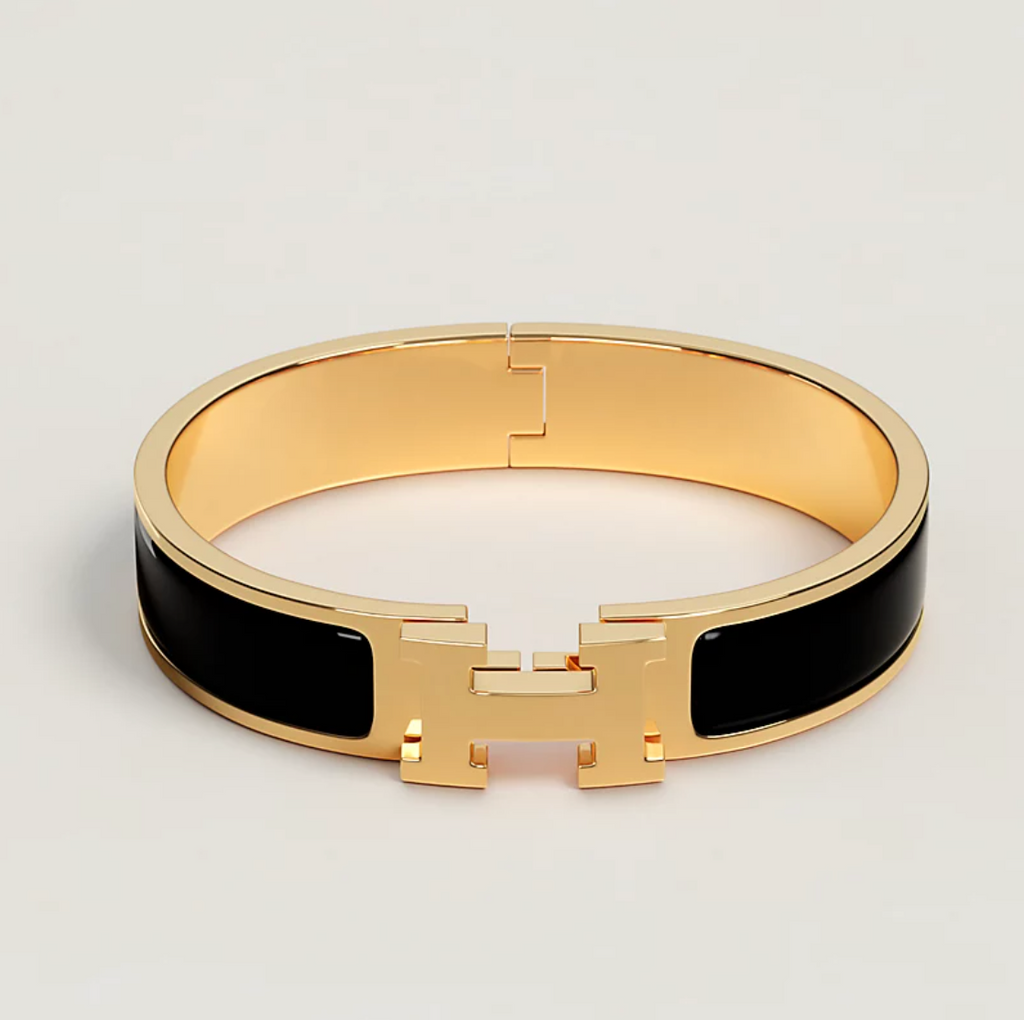 Gold bracelet with black accents on a light gray background