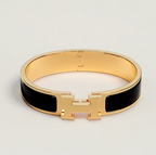 Gold bracelet with black accents on a light gray background