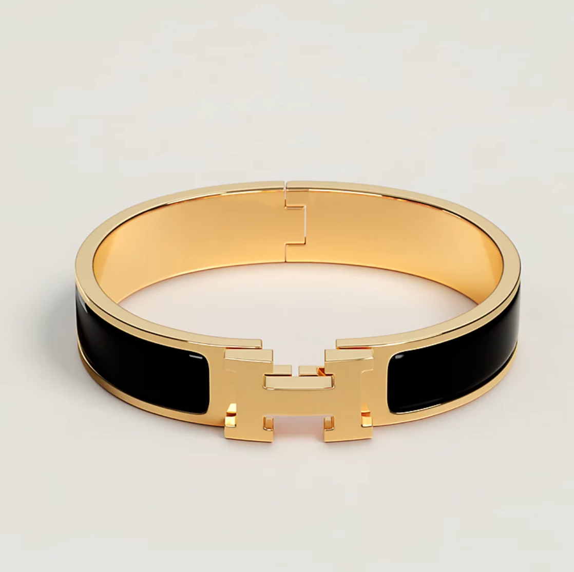 Gold bracelet with black accents on a light gray background