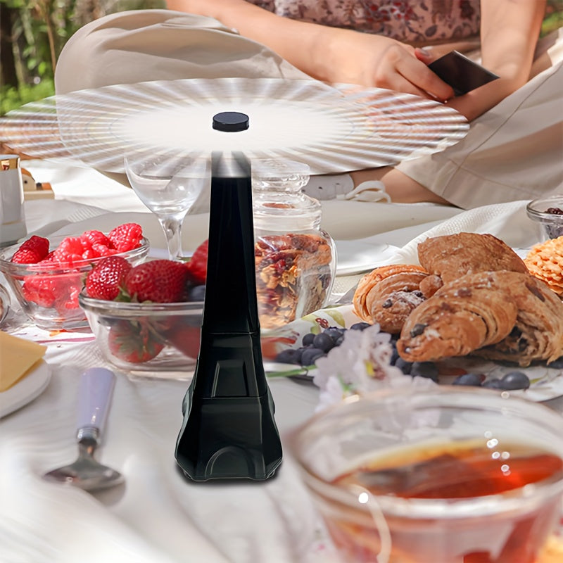 Black portable lamp on a table with food and people in the background