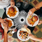 People enjoying a meal together with burgers, fries, and drinks on a patterned floor.