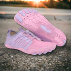 Pink and purple running shoes on a concrete surface with a sunset background