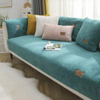 Teal sofa with decorative pillows and a magazine in a living room setting.