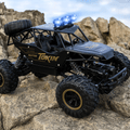 Black toy off-road vehicle with large wheels on rocky terrain, featuring the brand 'Tokin'.