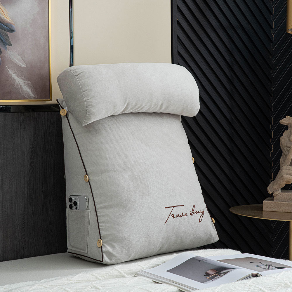 Gray wedge pillow on a bed with a decorative wall and statue in the background