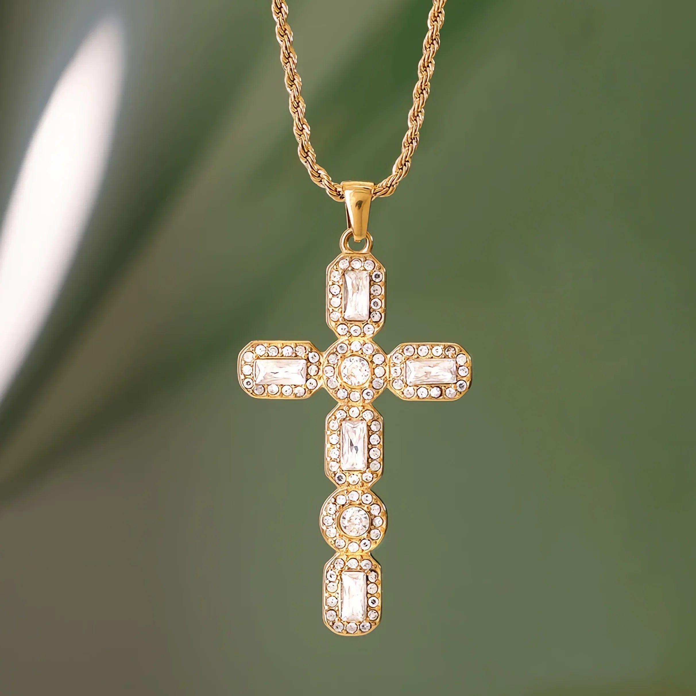 Gold cross pendant necklace on a green background