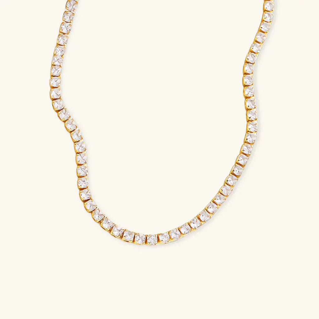 Gold necklace with clear stones on a white background