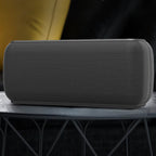 Black rectangular speaker on a dark surface with a blurred background
