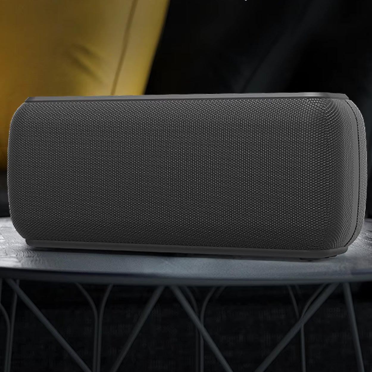 Black rectangular speaker on a dark surface with a blurred background
