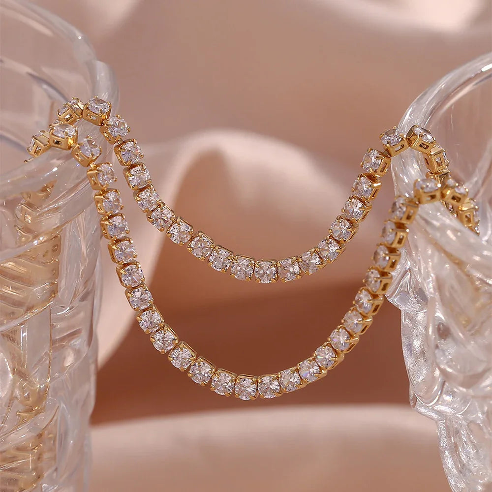 Gold hoop earrings with clear gemstones on a decorative stand.